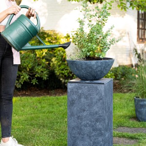 Dunkelgraue Pflanzschale Bowl Premium (55 cm) auf Säule, bewässert mit Gießkanne.