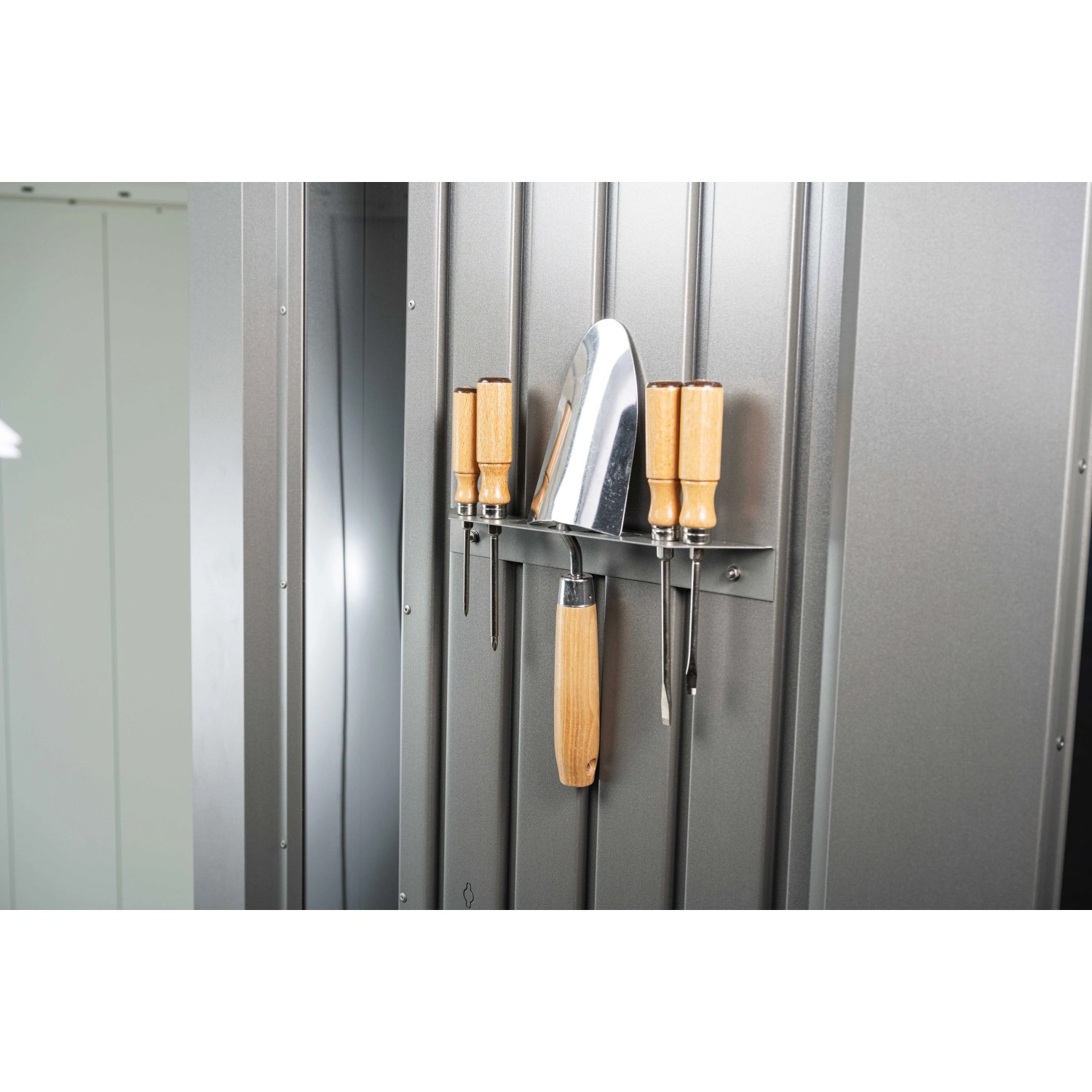 Innenansicht Biohort Gerätehaus Neo, dunkelgrau-metallic. Gartengeräte hängen an einer Leiste an der Metallwand.