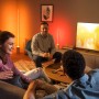 Philips Hue Gradient Signe Stehleuchte in Weiß im Wohnzimmer mit Personen.