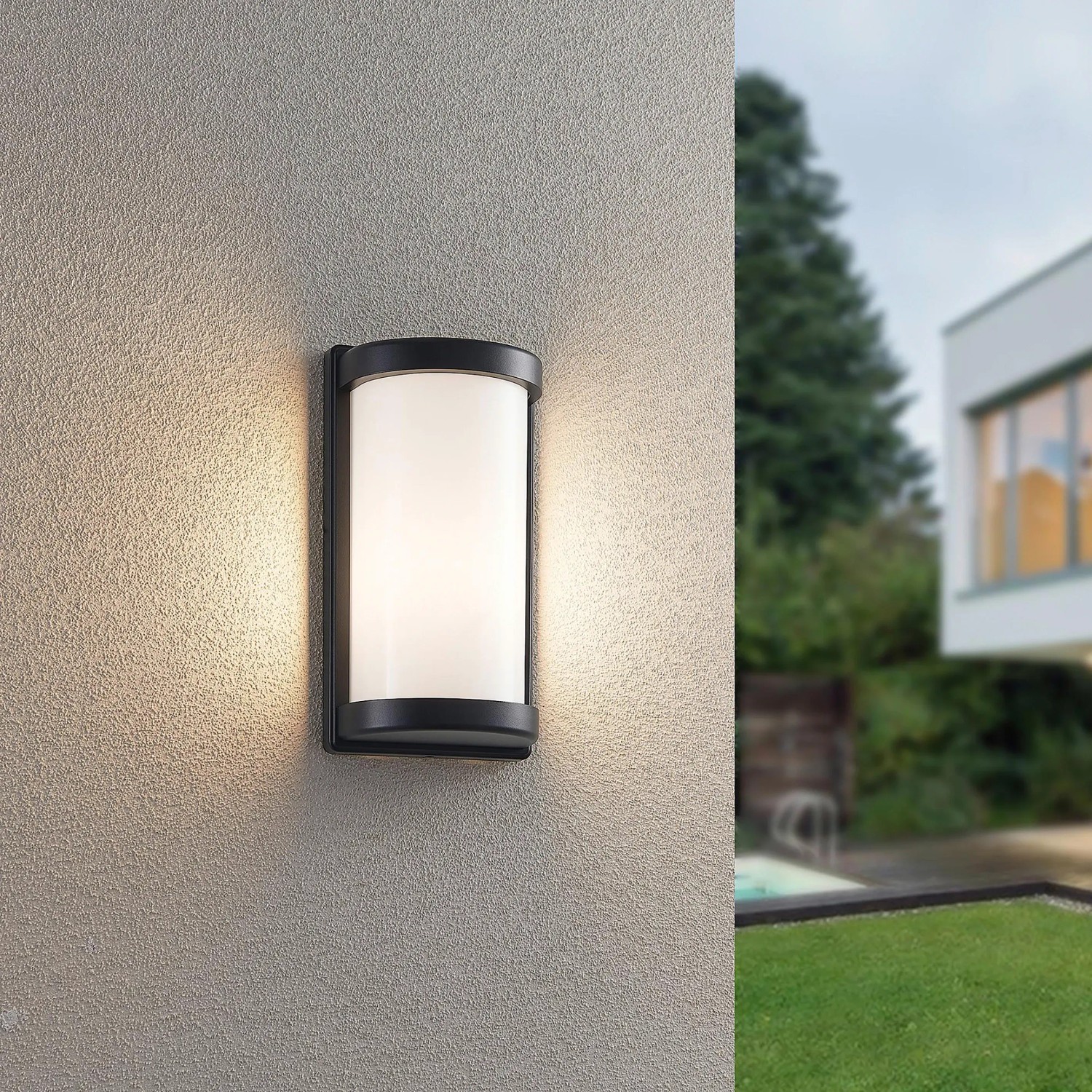 Moderne, schwarze Reality Außenwandleuchte Puelo mit zylindrischem Lampenschirm an Hauswand.