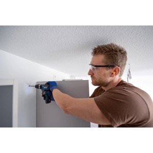 Mann bohrt mit Bosch Professional Akku-Schlagbohrschrauber GSB 12V-35 in Wand.