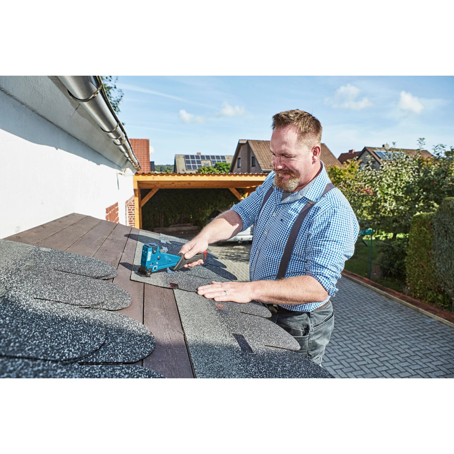 Mann befestigt Bitumenschindeln mit Novus Hammertacker J-055 auf einem Dach.