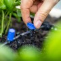 Hand reguliert blaues Ventil am LUX-TOOLS Tropf-Bewässerungs-Set. Bewässert Pflanzen im Garten mit Micro-Drip-System.