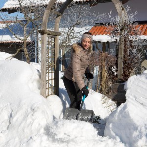 Frau räumt Schnee mit Gardena ClassicLine Schneeschieber. Winterdienst mit Schneeschaufel.