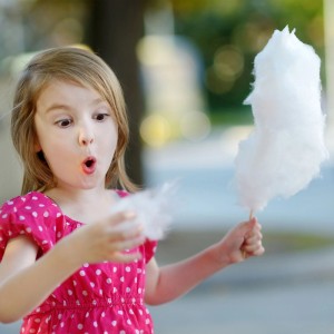 Mädchen isst Zuckerwatte am Holzstab, zubereitet mit Bambus Schaschlikspießen.