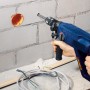LUX Mauerdurchbruchbohrer Comfort im Einsatz an einer Wand mit Bohrloch und Kabeln.