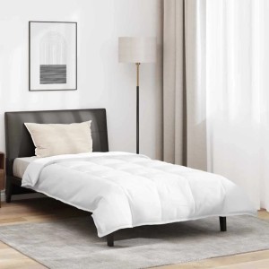 Weiße Daunenfeder-Bettdecke und Kissen auf Einzelbett in modernem Schlafzimmer. Gestepptes Design für Komfort.