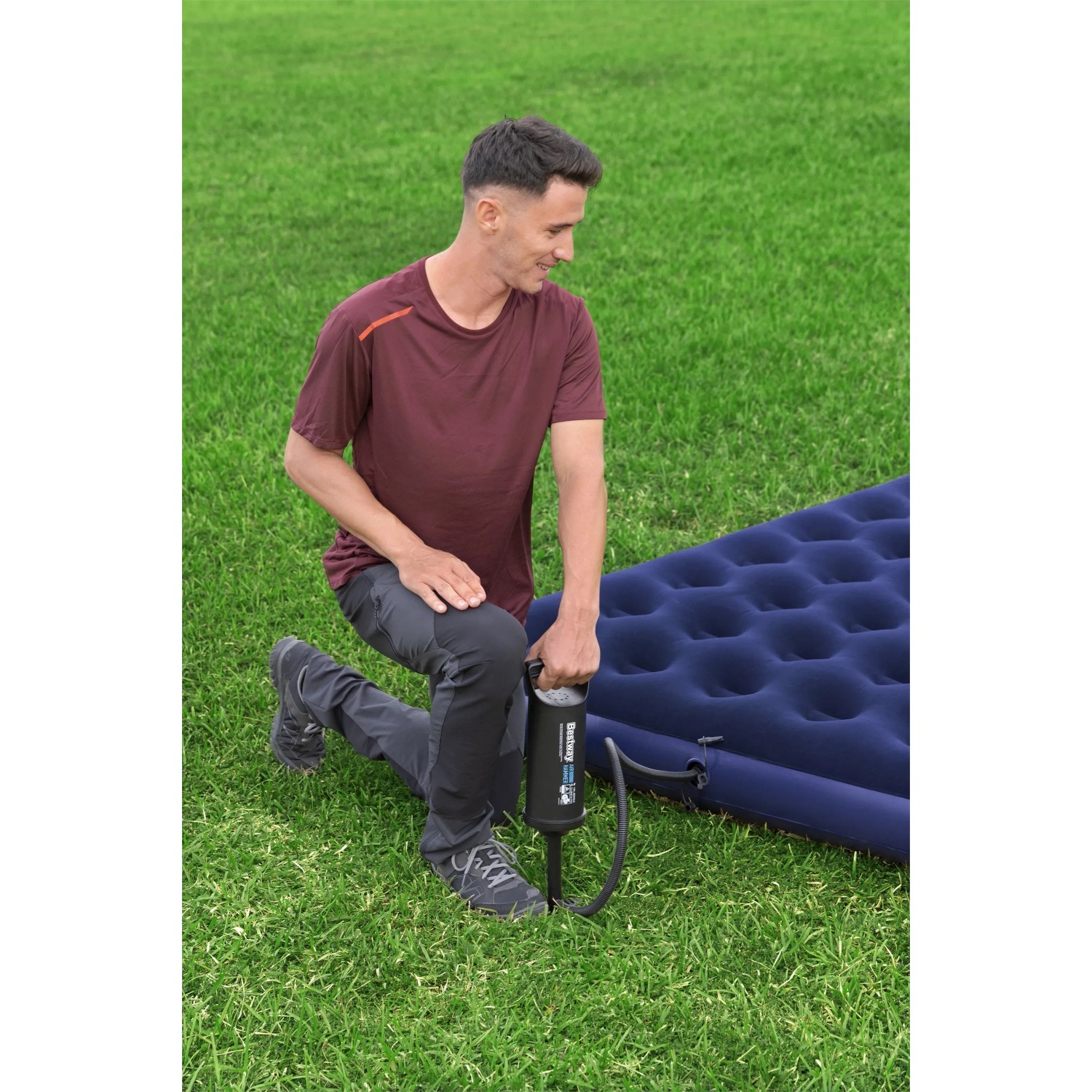 Mann pumpt Luftmatratze mit Bestway Air Hammer Handpumpe (1.850 ml) auf. Camping Zubehör.
