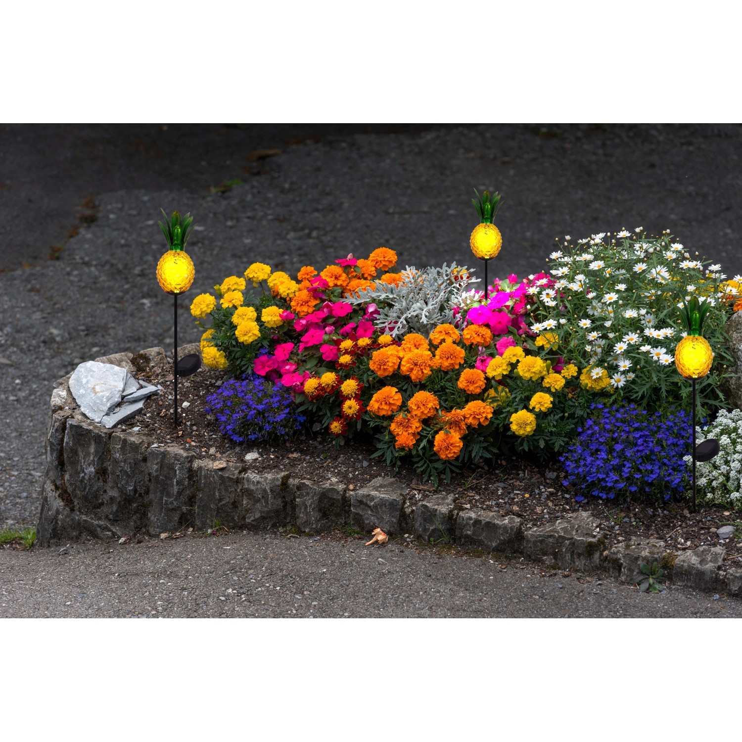 Orangefarbener LED-Solar-Erdspieß Ananas (81 cm) als Deko im Blumenbeet.