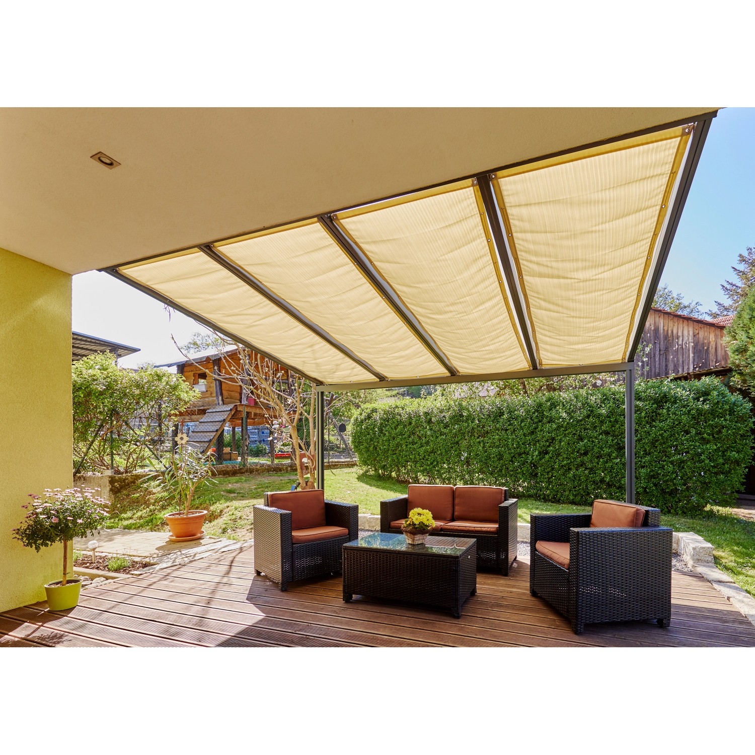 Sandsteinfarbene Gutta Seilspannmarkise (945 mm x 2.900 mm) über einer Terrassenüberdachung mit Sitzgruppe.
