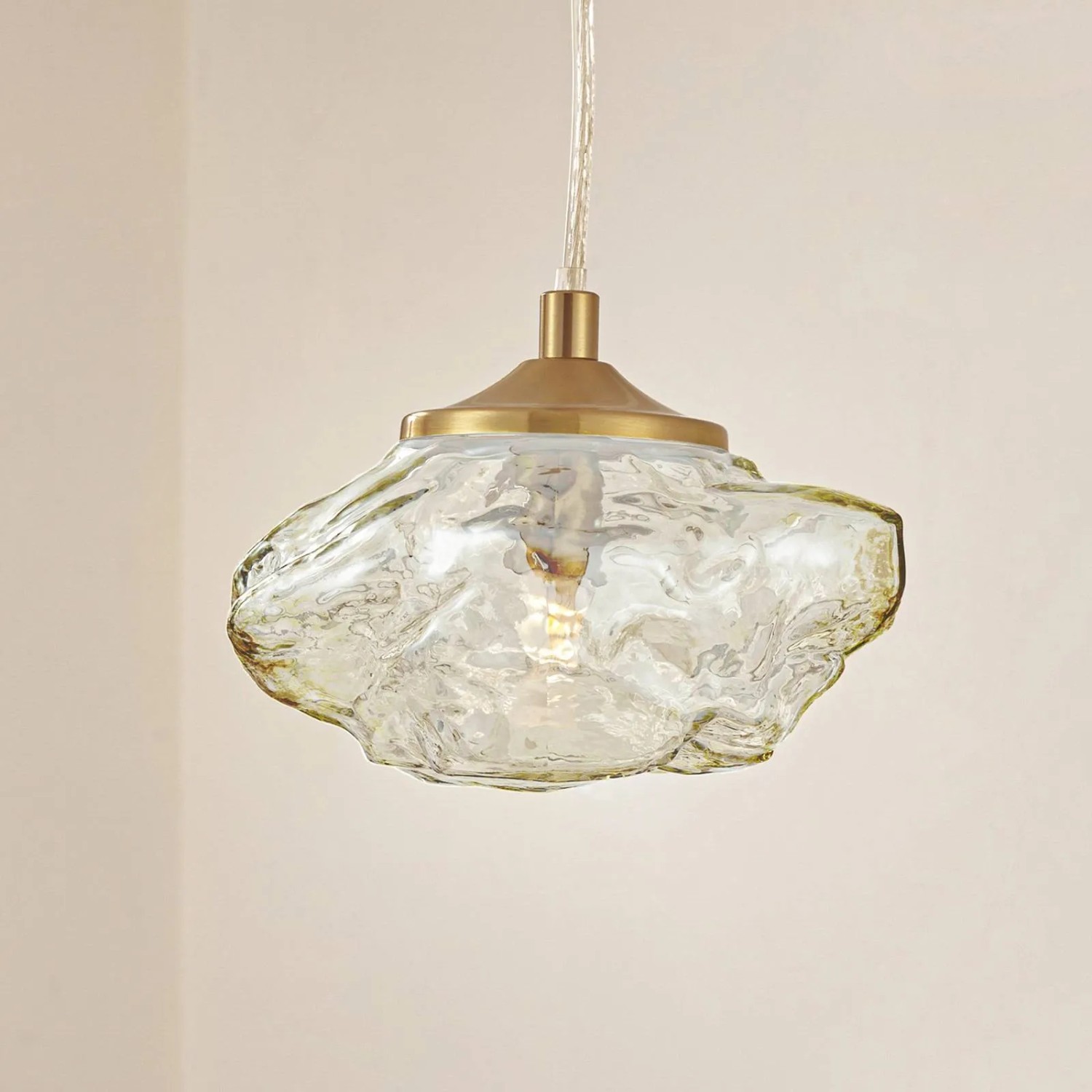 Moderne Lindby Pendelleuchte Piatra in Creme mit Glas Lampenschirm und messingfarbener Halterung.