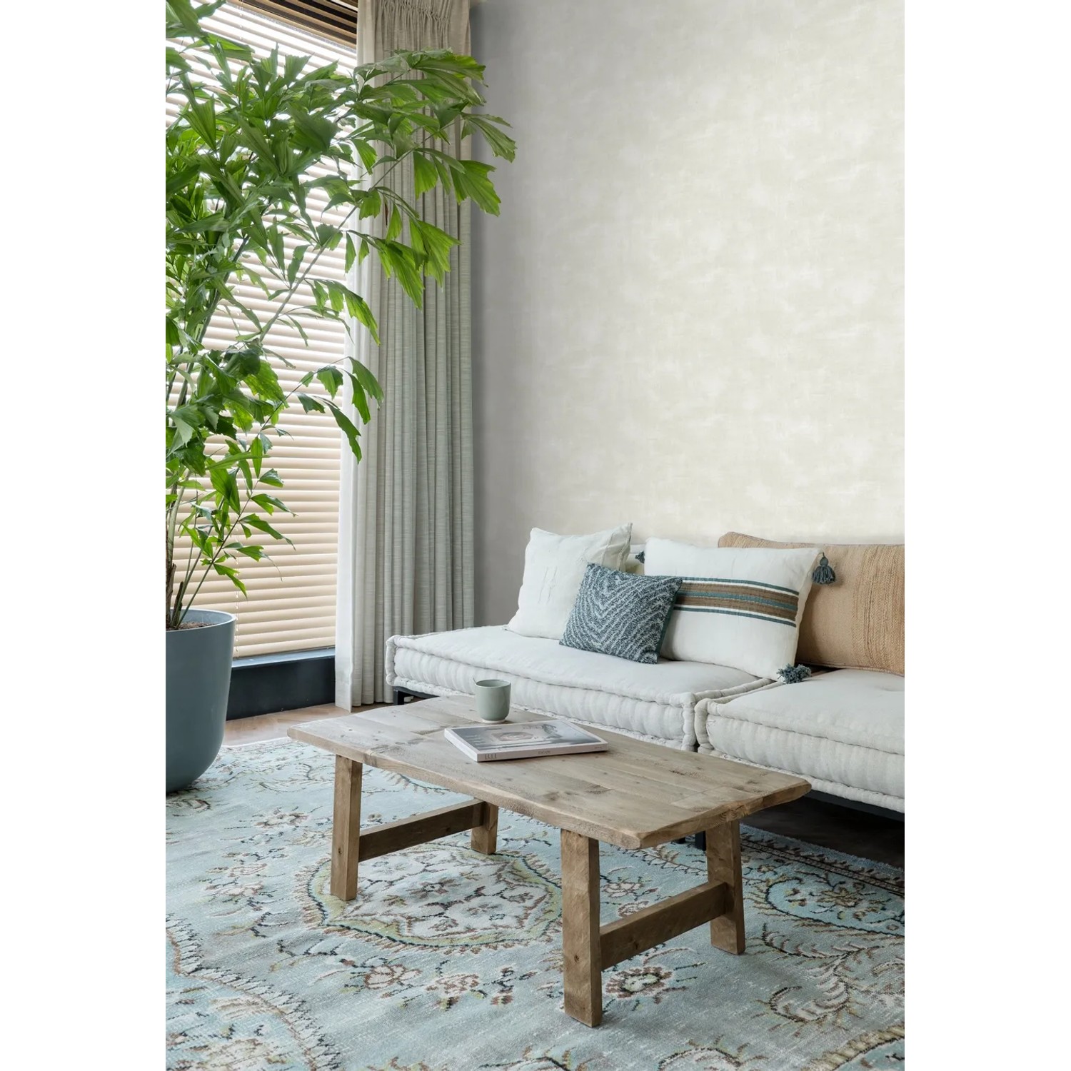 Wohnraum mit ESTAhome Tapete Betonoptik hellbeige, passend zu Teppich und Möbeln.