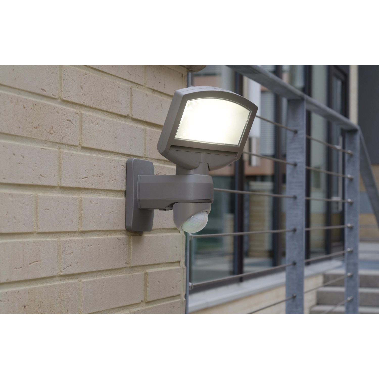 Lutec Solar LED-Strahler Sunshine mit Solarpanel an einer Wand. Außenstrahler mit Bewegungsmelder.