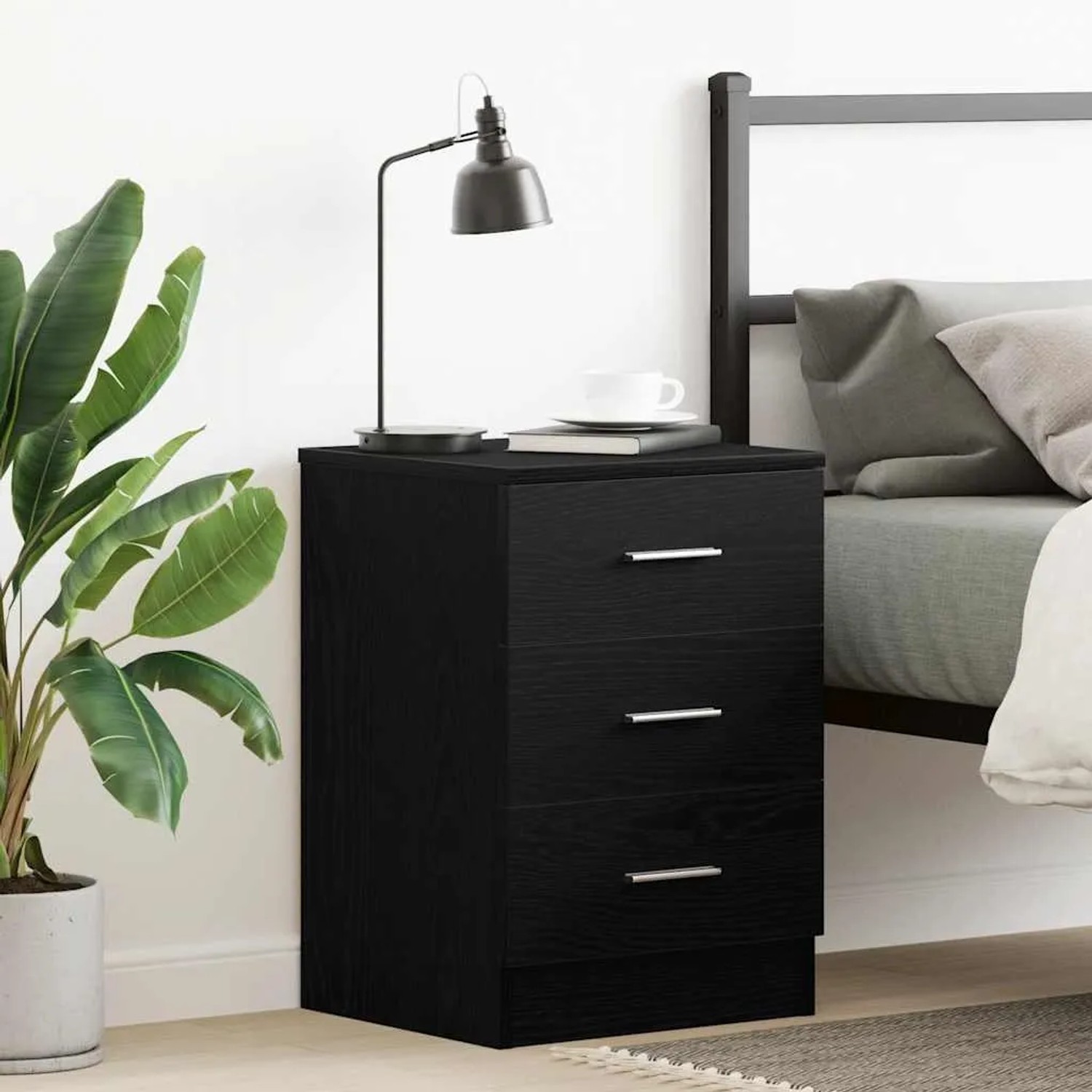 Schwarzer Nachttisch aus Holzwerkstoff mit drei Schubladen im Schlafzimmer.