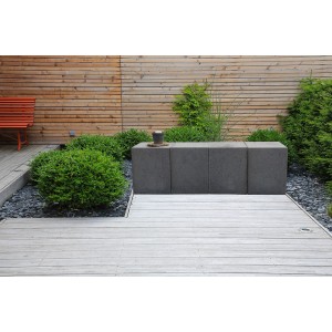 Grauer Beton U-Stein (40x50x40 cm) als Bankelement im Garten, kombiniert mit Holzelementen und Pflanzen.