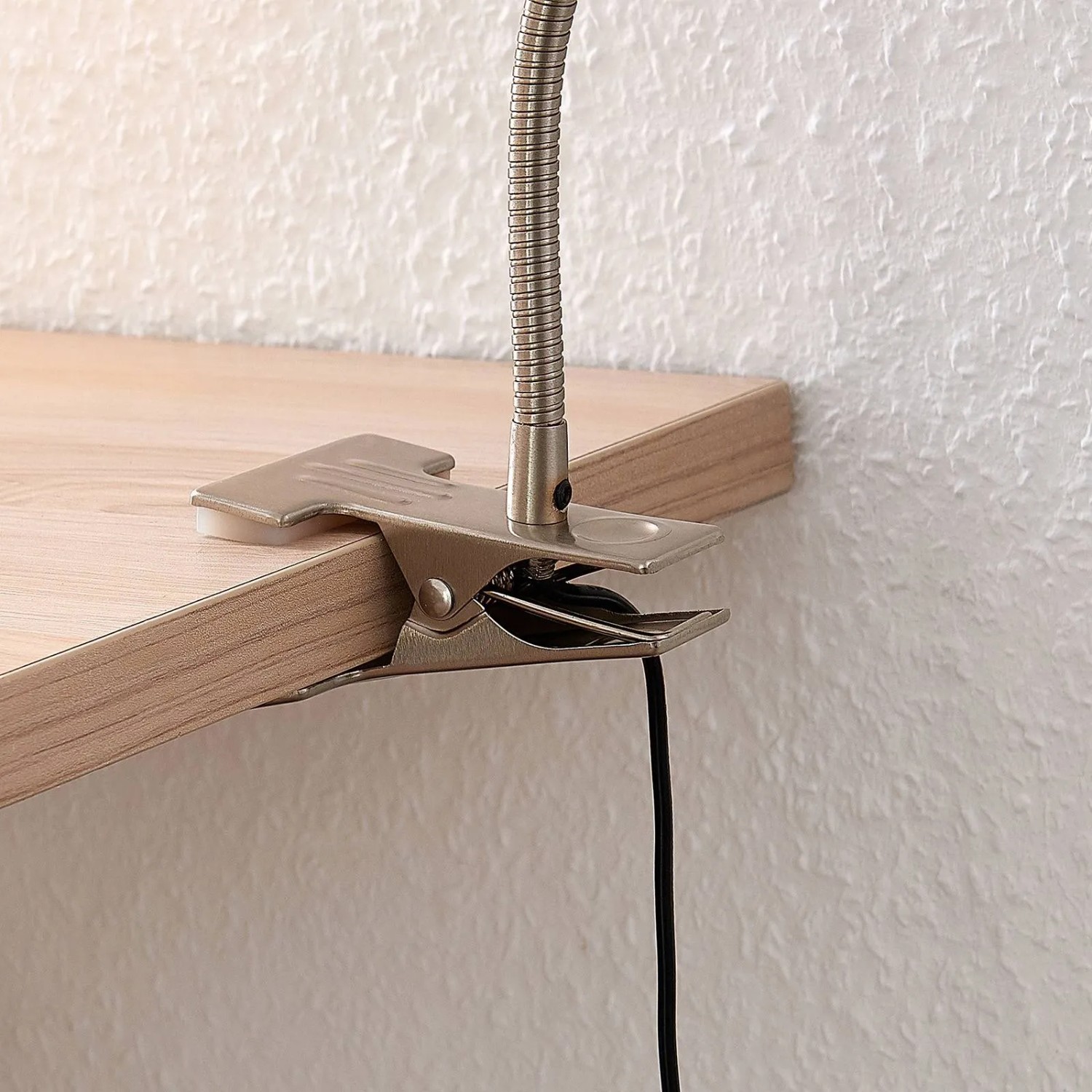 Detailaufnahme: Lindby LED Klemmleuchte Djamila in Alu am Tisch befestigt.