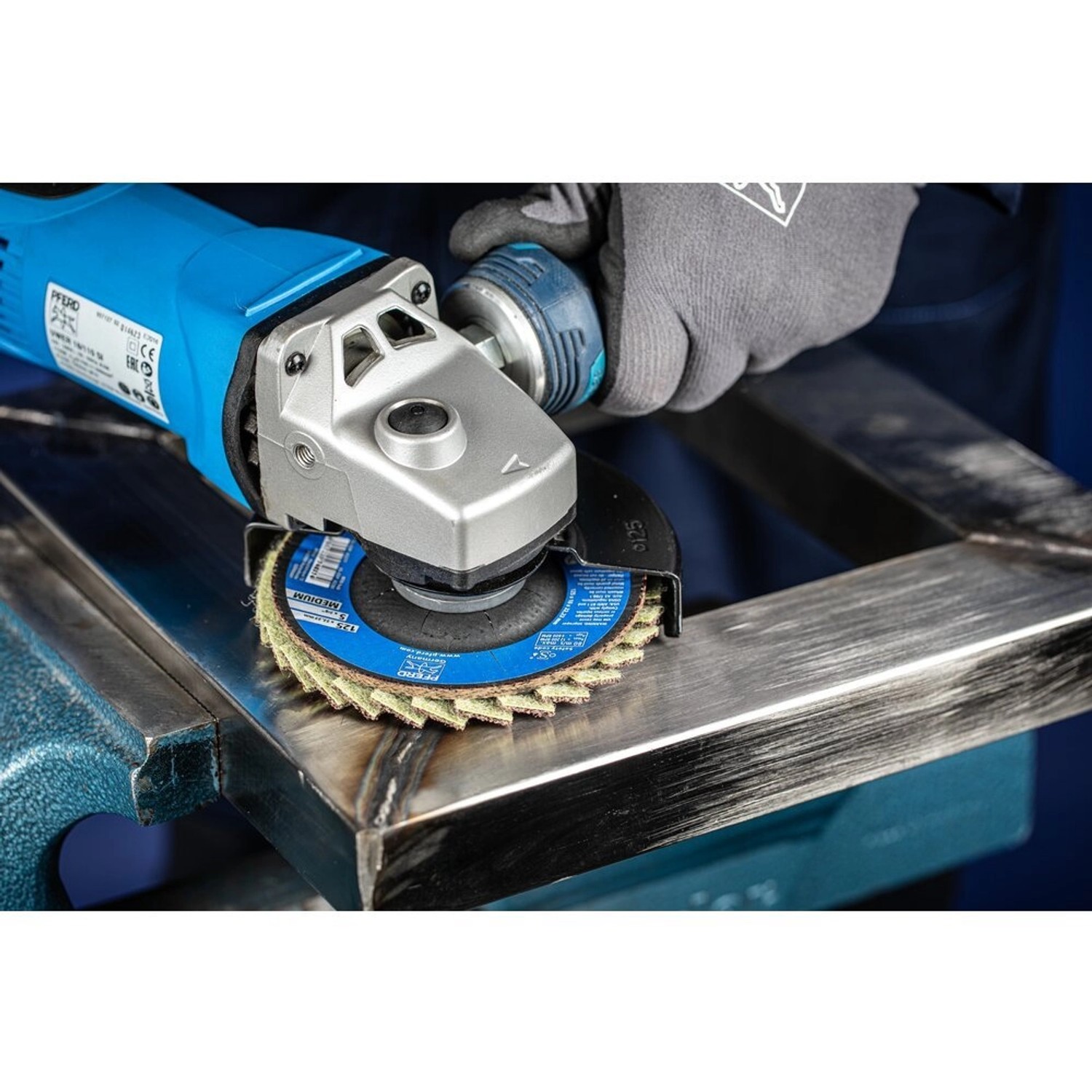 Pferd Vlieswerkzeug PVL 125 mm im Einsatz beim Schleifen von Metall mit einer Schleifmaschine.