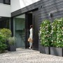 Elho Vivo Next Lang Pflanzkübel in Schwarz mit Rollen vor modernem Haus.
