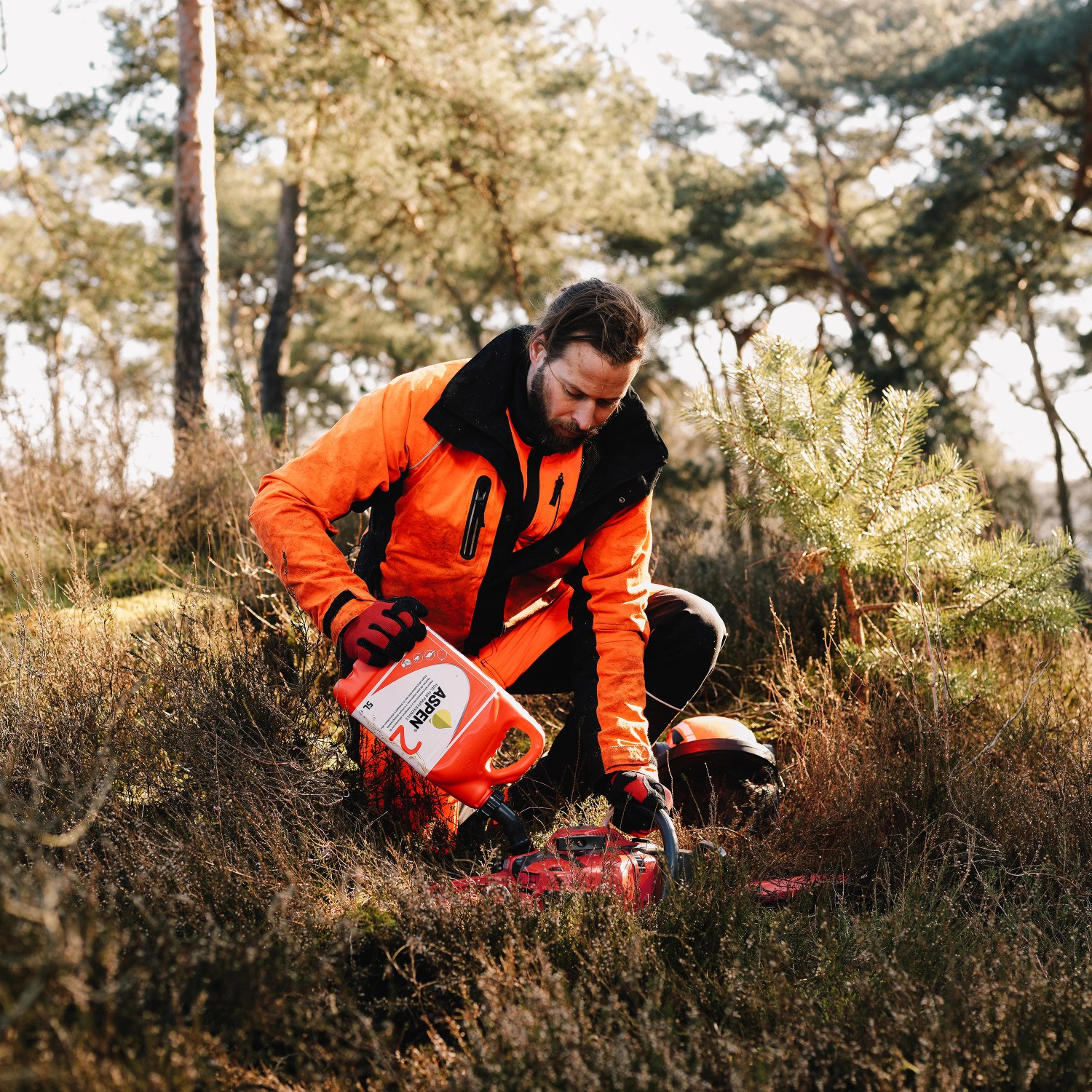 Mann füllt Aspen 2-Takt Gemisch in Kettensäge. Sonderkraftstoff für Motorsägen.
