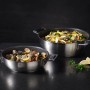 Zwei RÖSLE Servierpfannen SILENCE PRO aus Edelstahl mit ProResist Antihaftbeschichtung, gefüllt mit Pasta und Muscheln, bereit zum Servieren.