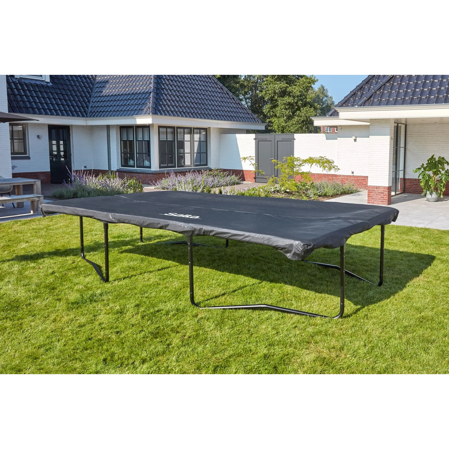 Schwarze Salta Wetterschutz-Abdeckung auf rechteckigem Trampolin im Garten.