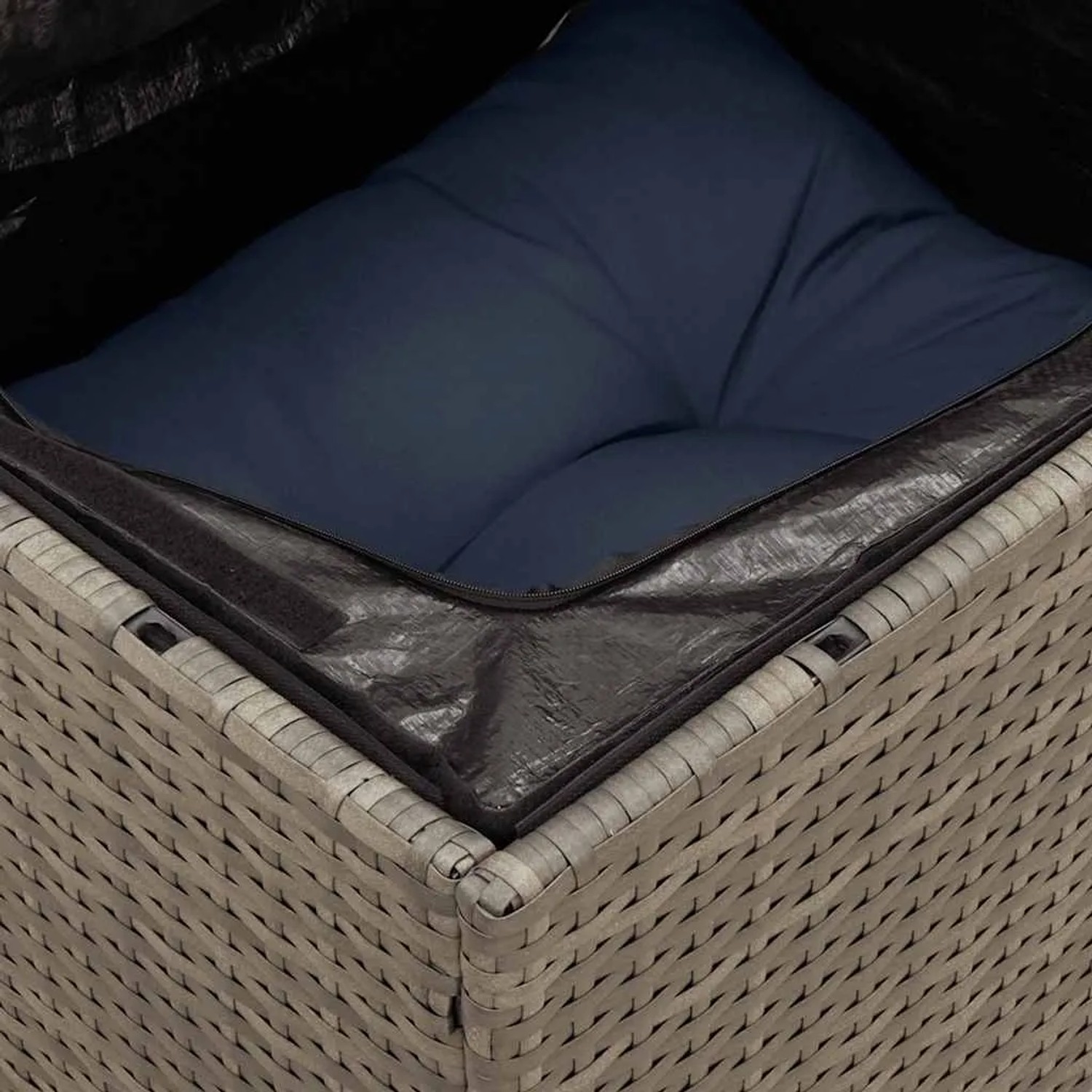 Detailaufnahme: Graues Rattan Gartensofa mit blauem Kissen und wasserdichtem Staufach.