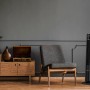 Brandson Turmventilator 96cm in Grau, stehend im Wohnraum neben Sessel und Kommode.