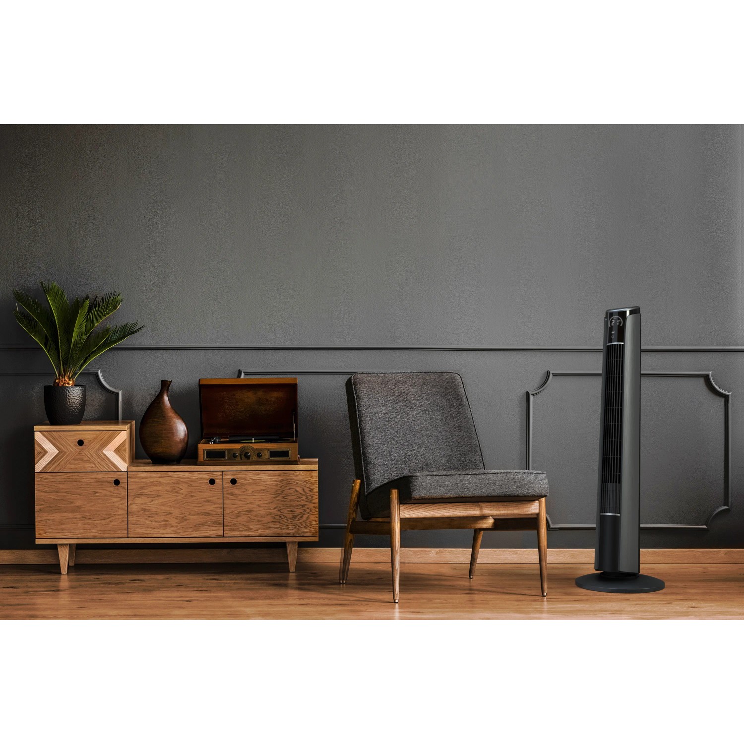 Brandson Turmventilator 96cm in Grau, stehend im Wohnraum neben Sessel und Kommode.
