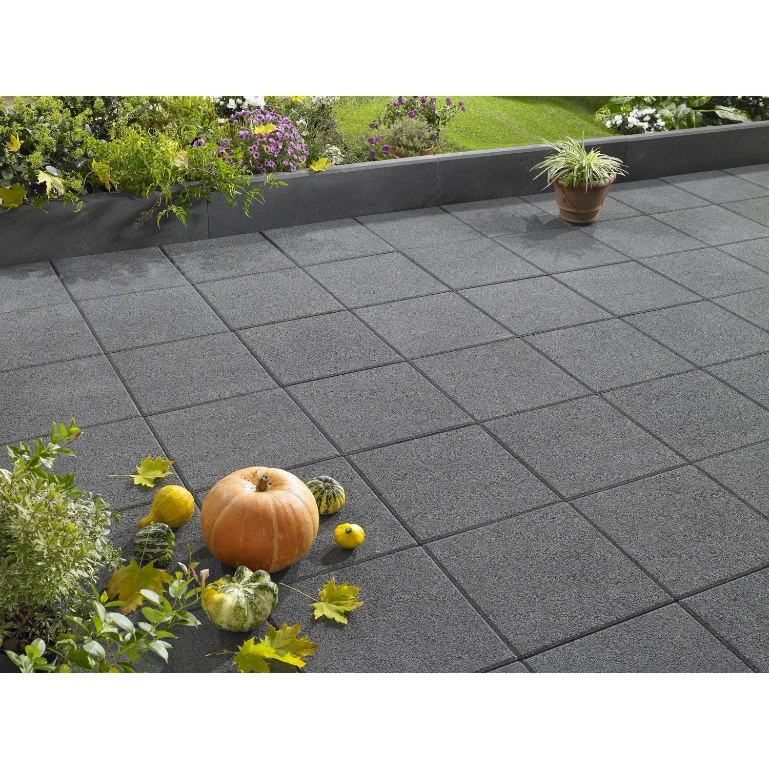 Verlegte, anthrazitfarbene Terrassenplatten Vicenza 40x40 cm mit Kürbis-Deko auf Terrasse.