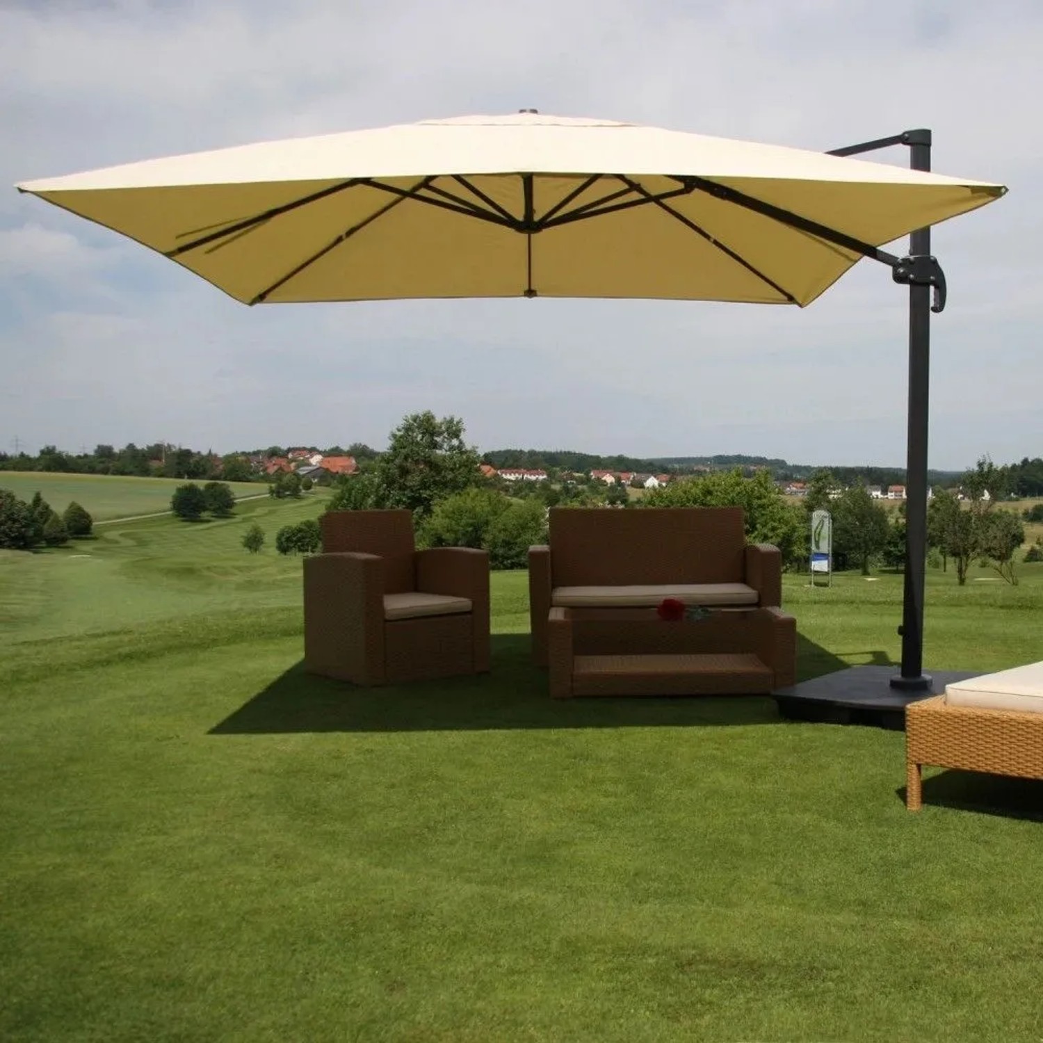 Cremefarbener MCW Ampelschirm 3x3m mit Aluminiumgestell und Ständer über Gartenmöbeln auf Rasen.