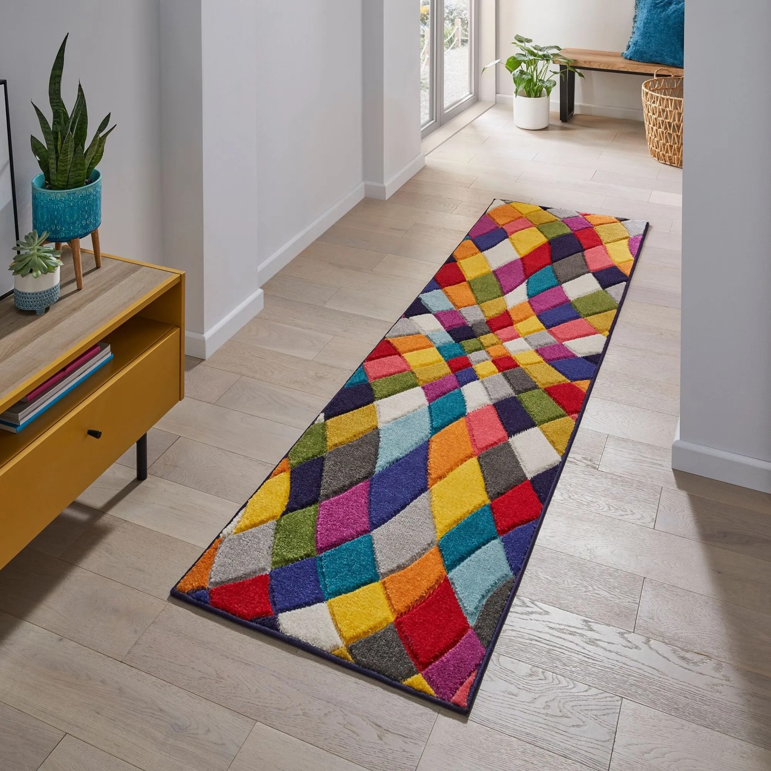 Mehrfarbiger Flair Rugs Kinderteppich Rhumba mit lebhaftem, geometrischem Muster im Flur auf Holzfußboden.