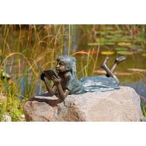 Rottenecker Bronze-Figur Lara, lesendes Mädchen als Gartendeko auf Stein vor Teich.