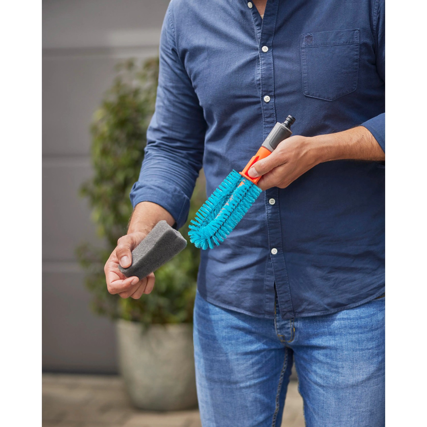 Mann hält Gardena Cleansystem Fahrradbürste (blau) mit Schwamm, geeignet zur Fahrradreinigung.