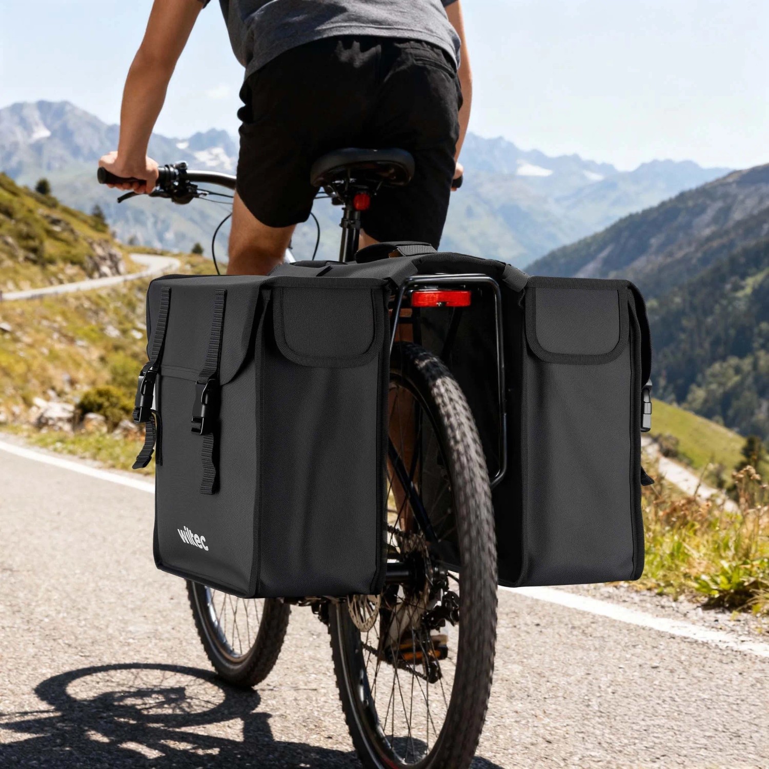 Schwarze Wiltec Doppel-Gepäckträgertasche 30L am Fahrrad auf Bergstraße. Wasserresistente Fahrradtasche für Touren.