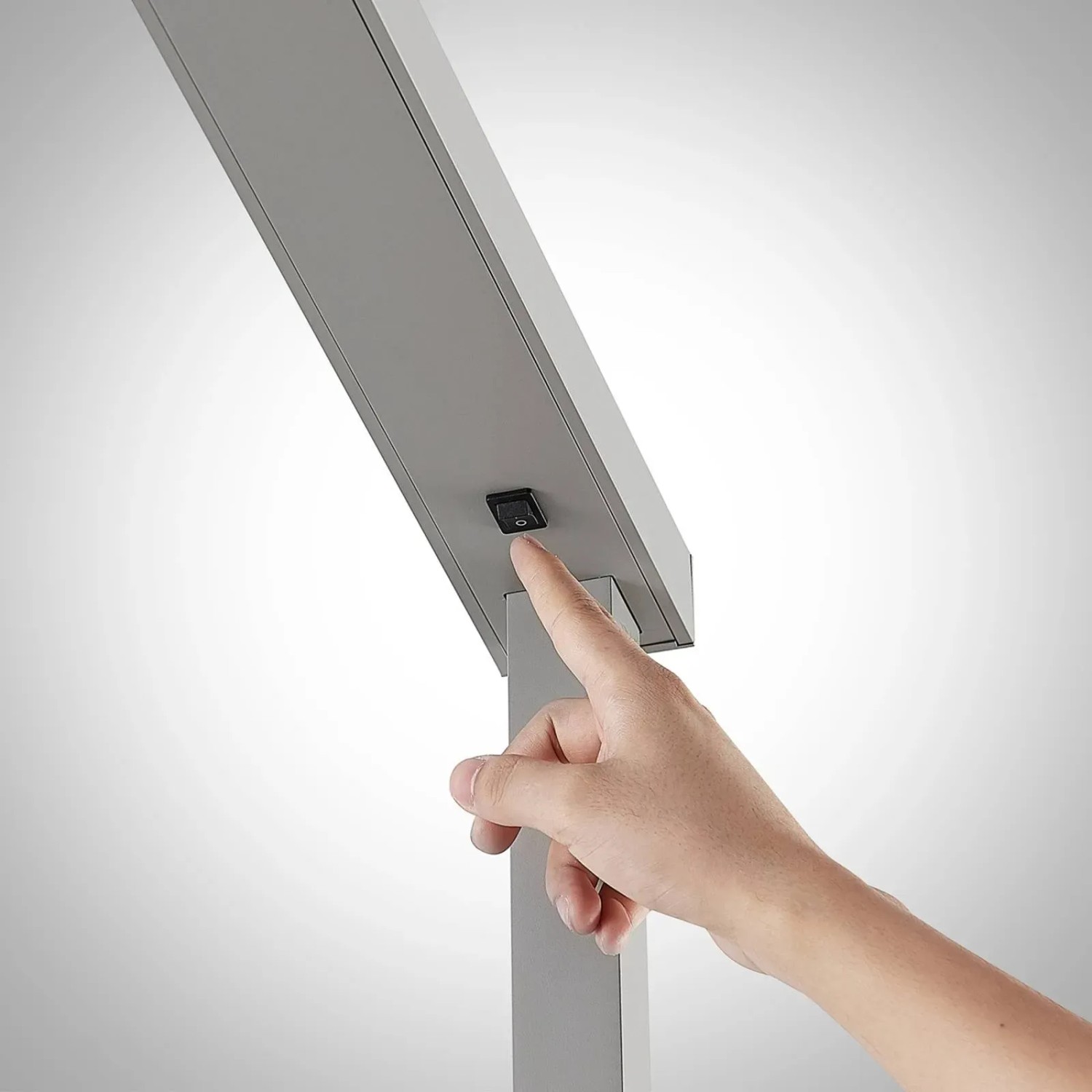 Detailaufnahme: Hand schaltet Arcchio LED Bürostehleuchte Tamilo in Alu ein/aus.