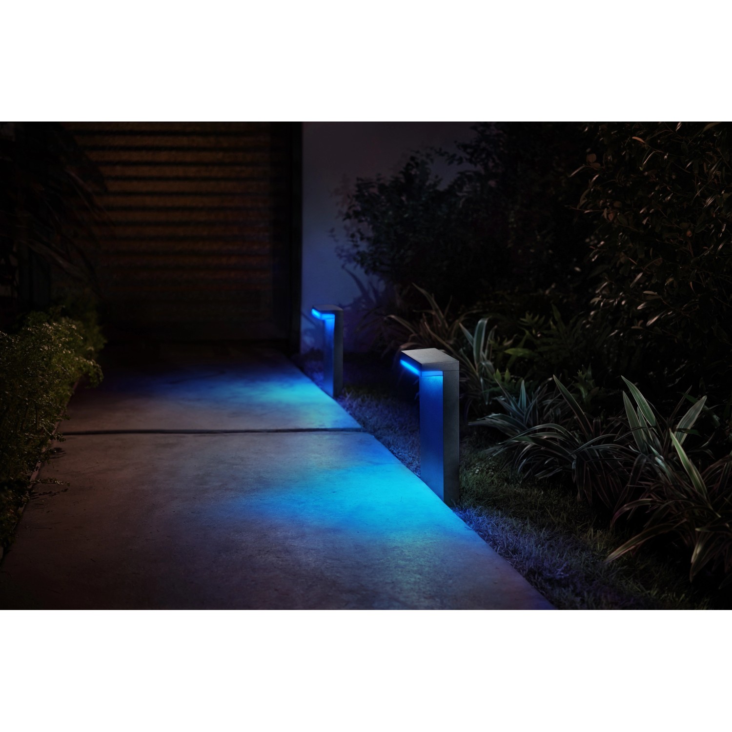 Philips Hue Nyro Sockelleuchte, schwarz, mit blauem Licht im Garten.