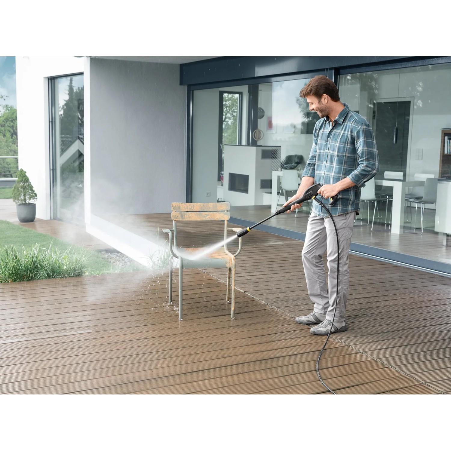 Mann reinigt Gartenstuhl mit Kärcher Hochdruckreiniger K 2 Power Control. Effiziente Reinigung im Außenbereich.