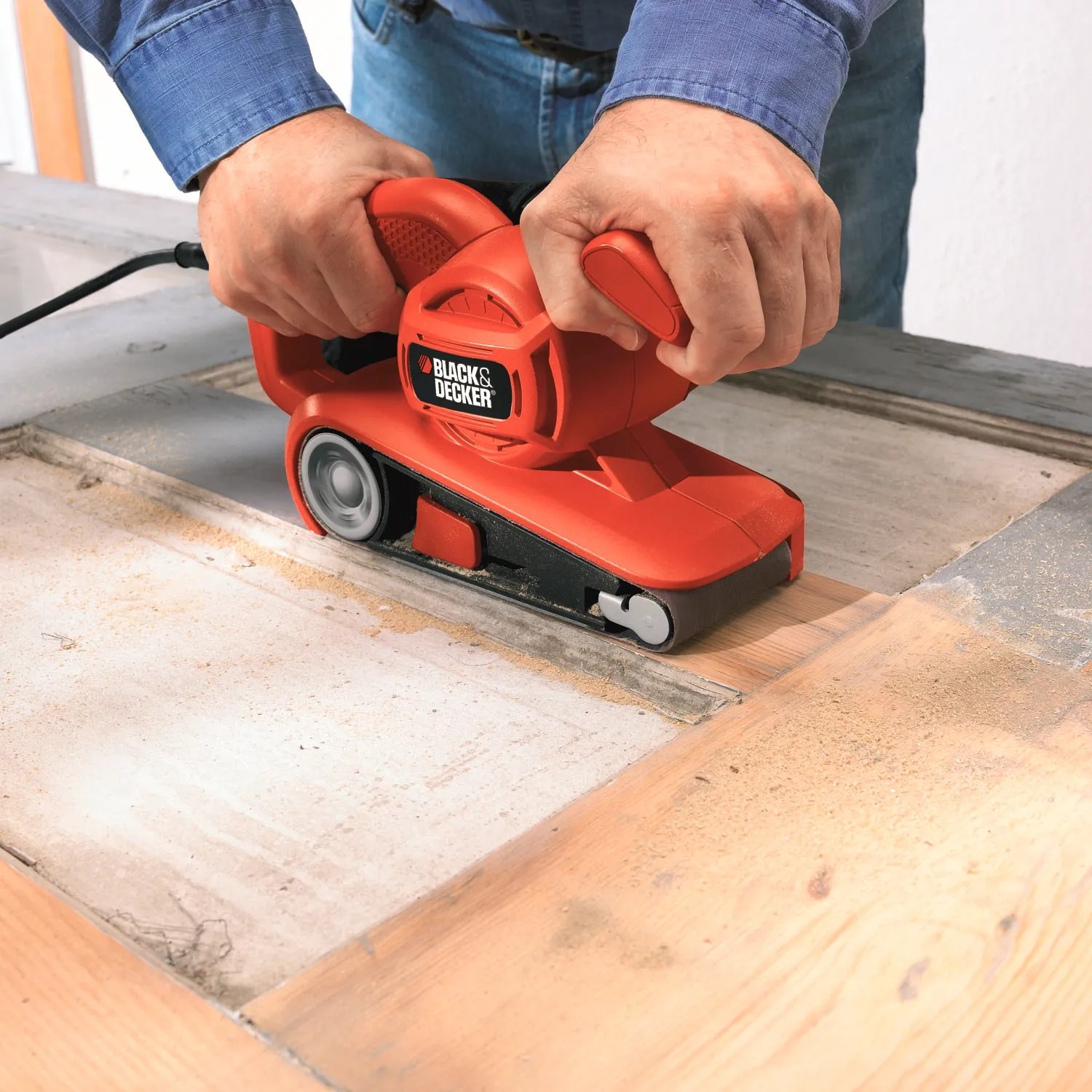 Black+Decker Bandschleifer KA86 in Aktion beim Schleifen von Holz. Rotes Gehäuse, ergonomischer Griff.