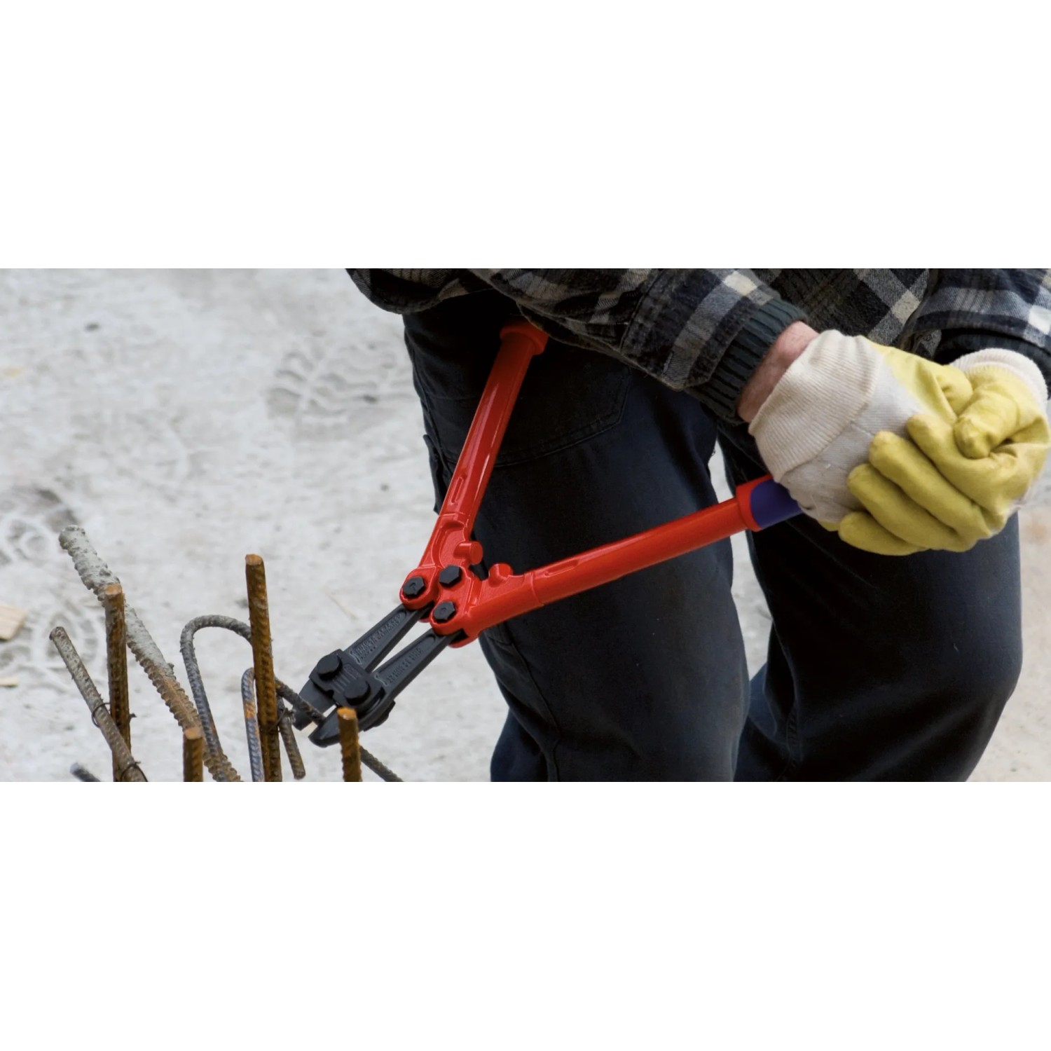 Mann schneidet mit Knipex Bolzenschneider Stahl. Zange mit roten Griffen.