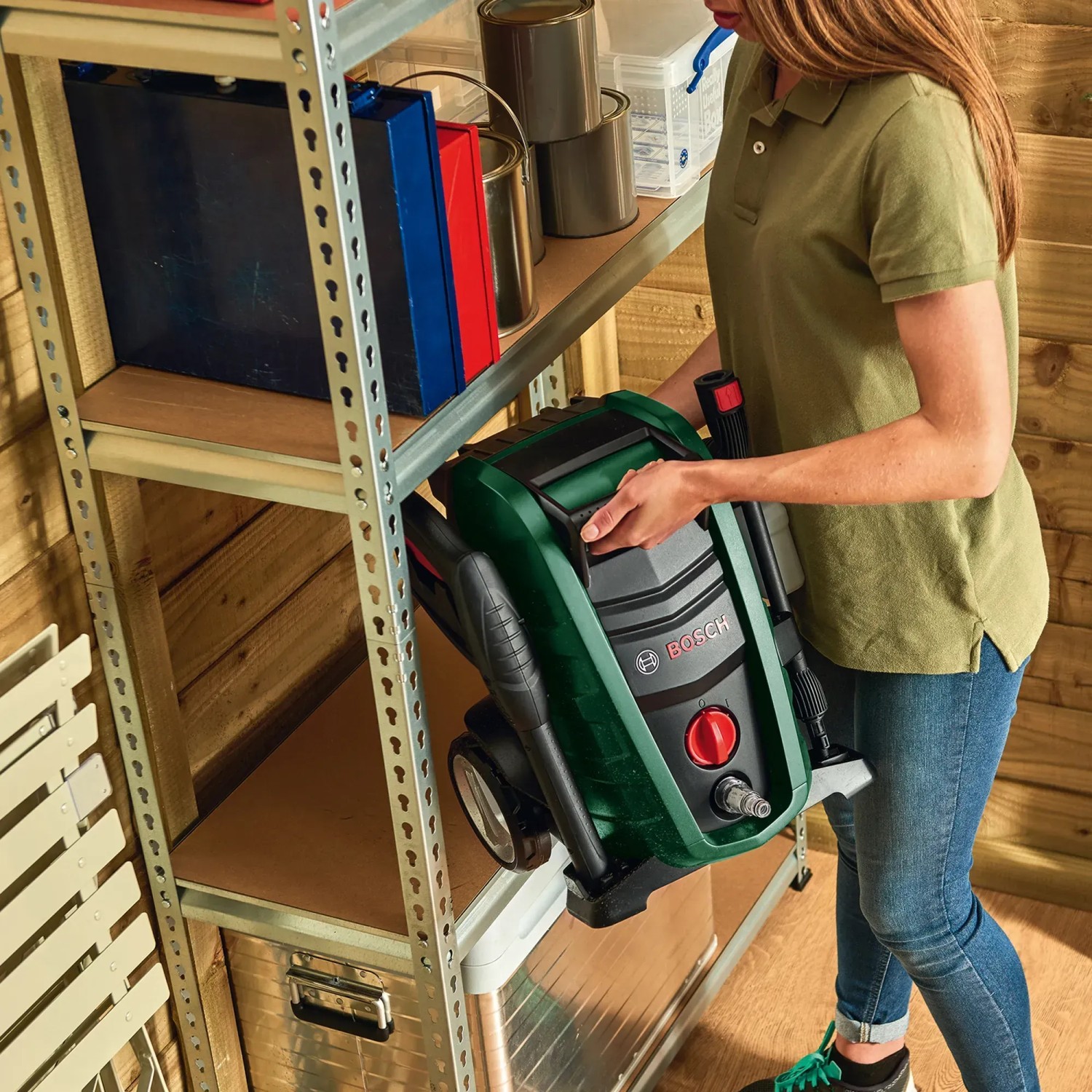 Bosch Hochdruckreiniger UniversalAquatak 125 wird von einer Frau aus einem Regal genommen.