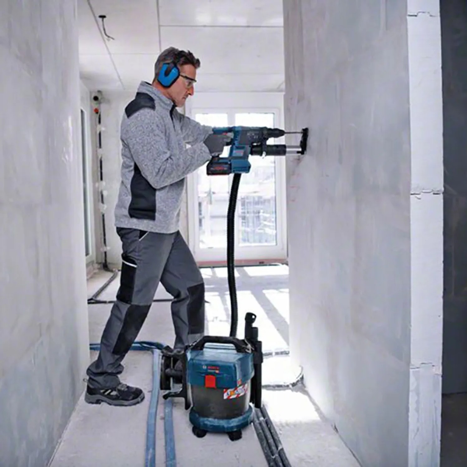 Bosch Professional Akku-Industriestaubsauger GAS 18V-10 L im Einsatz mit Bohrmaschine.