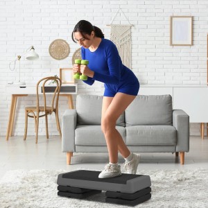 Frau trainiert mit Aerobic Stepper SPORTNOW und Hanteln im Wohnzimmer.