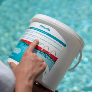 Eimer Bayrol Chlorifix 5 kg Pool Desinfektion mit Hand vor Poolwasser.