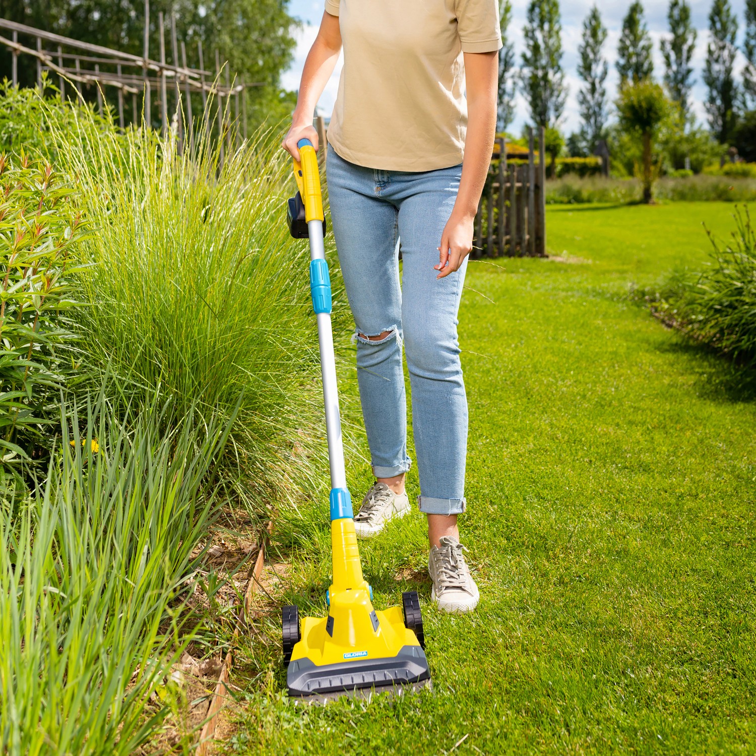 Frau benutzt Gloria Akku-Rasen- und Kantenschneider Finecut 18 V im Garten.