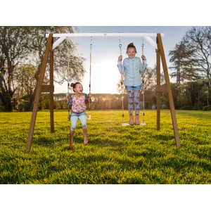 Axi Doppelschaukel aus Holz in Braun und Weiß mit zwei Kindern auf dem Rasen.