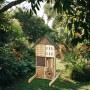 Holz-Insektenhotel Kobolo BEE mit grüner Dachspitze, gefüllt mit Bambus & Holz, im sonnigen Garten für Bienen & Nützlinge.