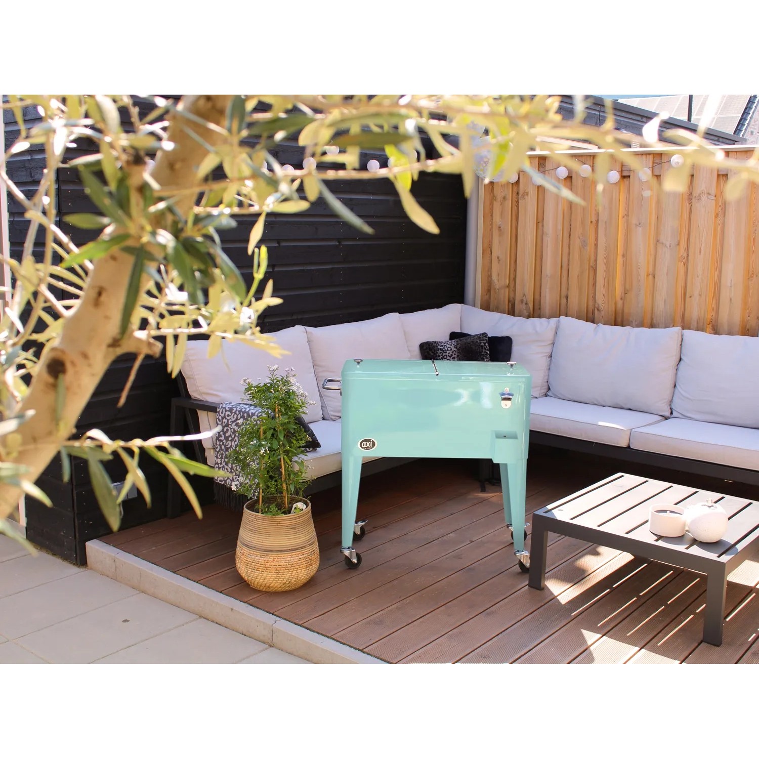 Axi Kühlwagen Retro Mint 76 l auf Terrasse mit Lounge-Möbeln und Tisch.
