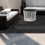 Dunkler KARAT Outdoor Teppich Lucca, stilvoller Balkonteppich nach Maß auf Terrasse mit Möbeln.