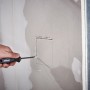 Wolfcraft Bohrsäge schneidet ein Loch in eine Gipskartonwand. Maurerwerkzeug für präzise Ausschnitte.