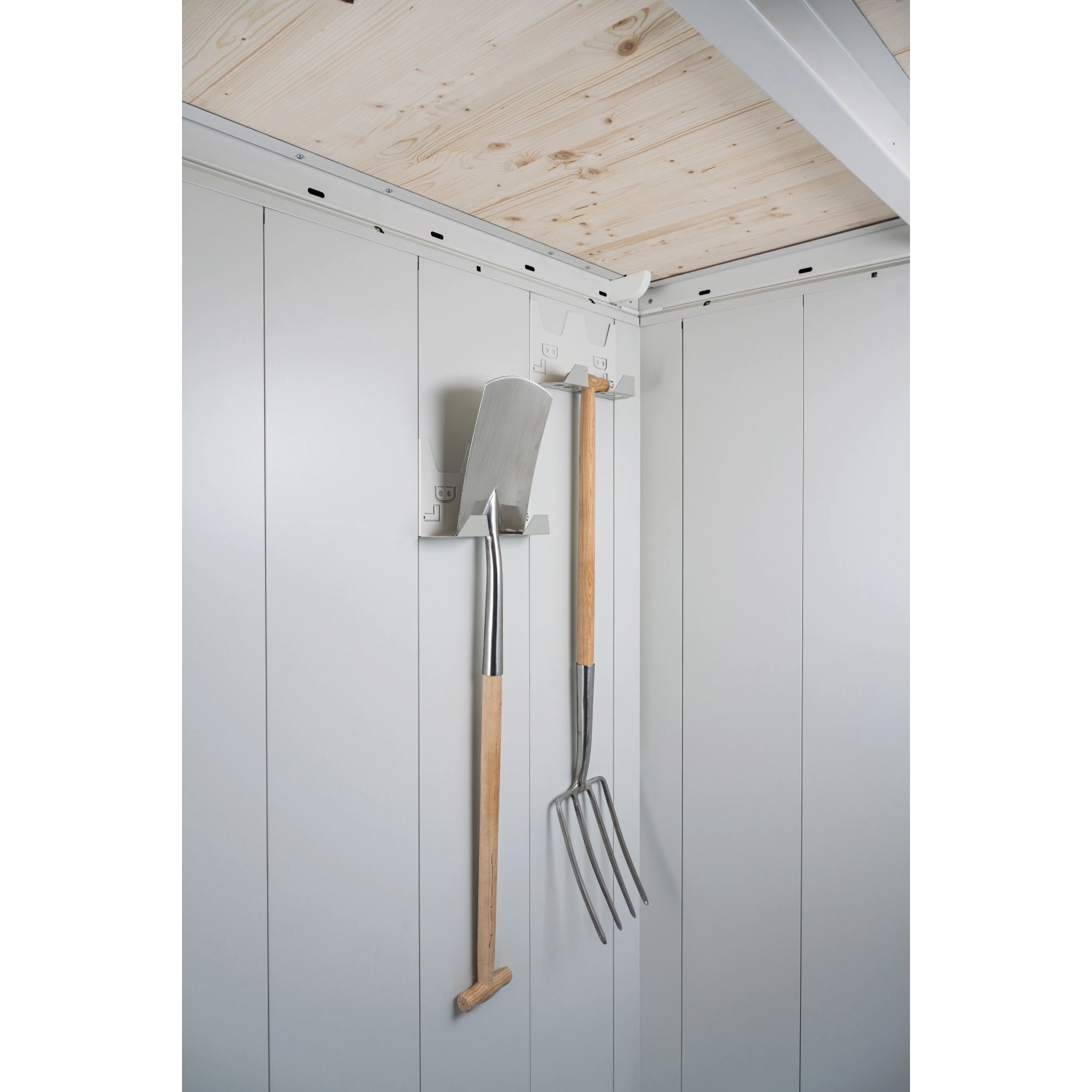 Innenansicht Biohort Gerätehaus Neo 2B. Spaten und Heugabel hängen an Wandhaken. Metallwände, Holzdecke.